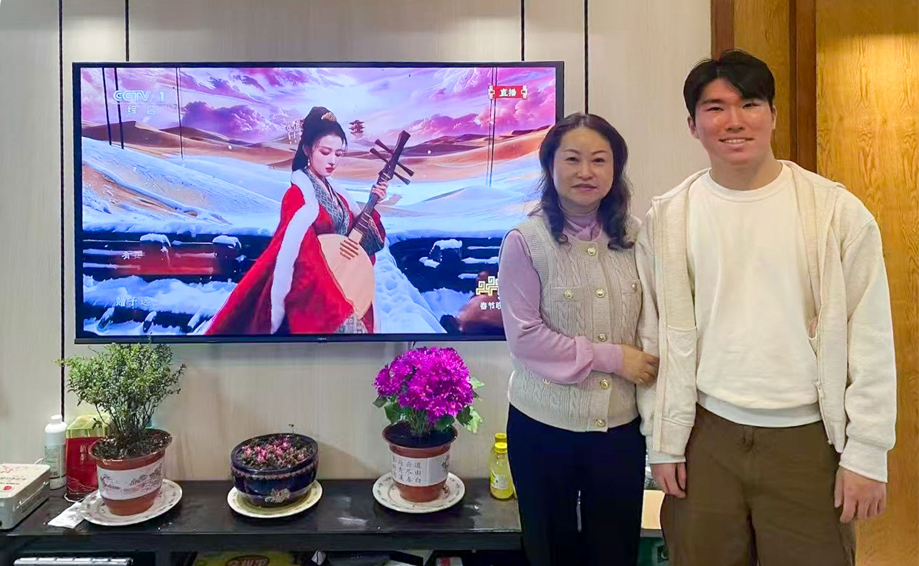 Jerry Ju NYU New York ’27 and his mother pose in front of the television during the Chunwan Gala 