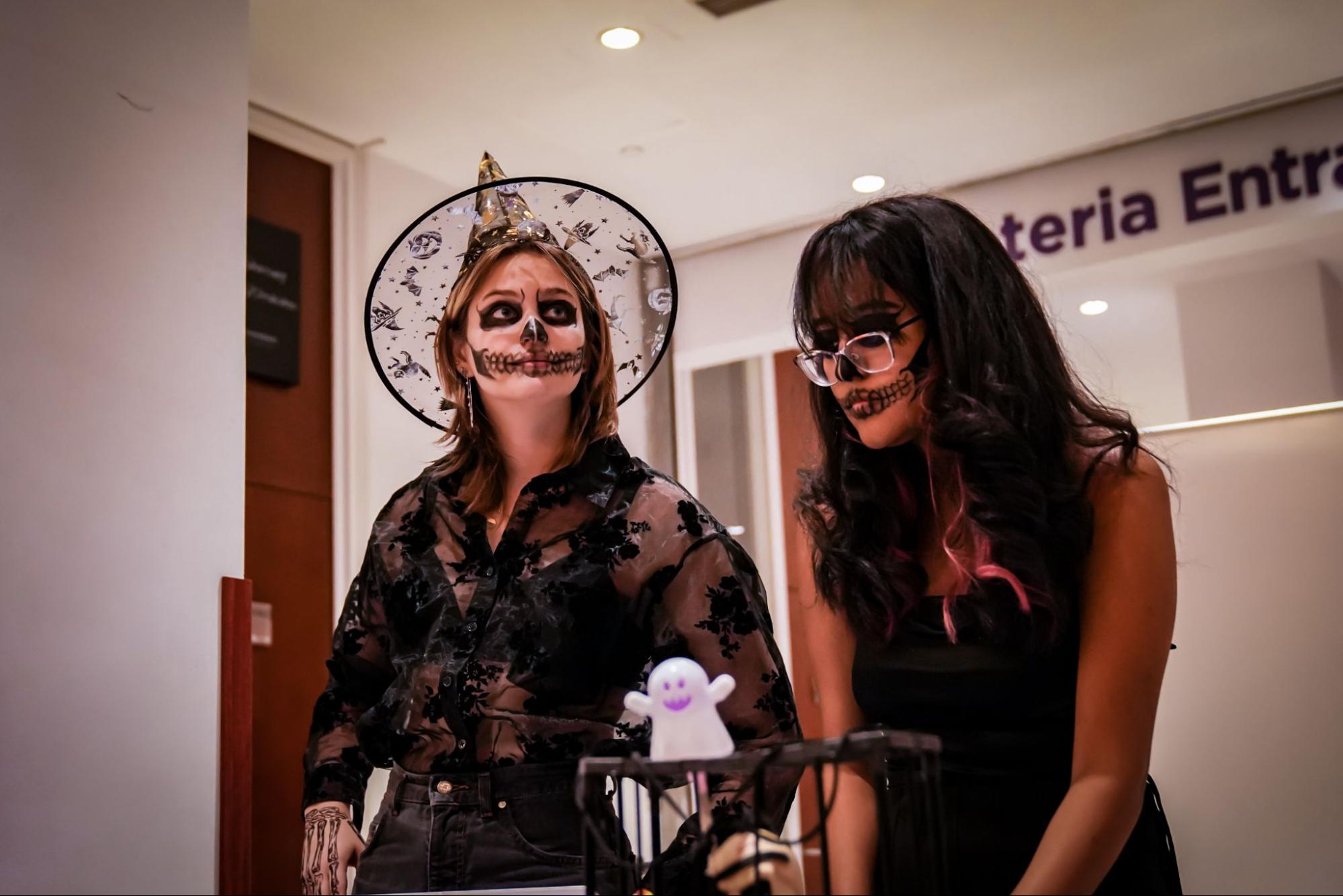 Two students stand in black halloween costumes. 