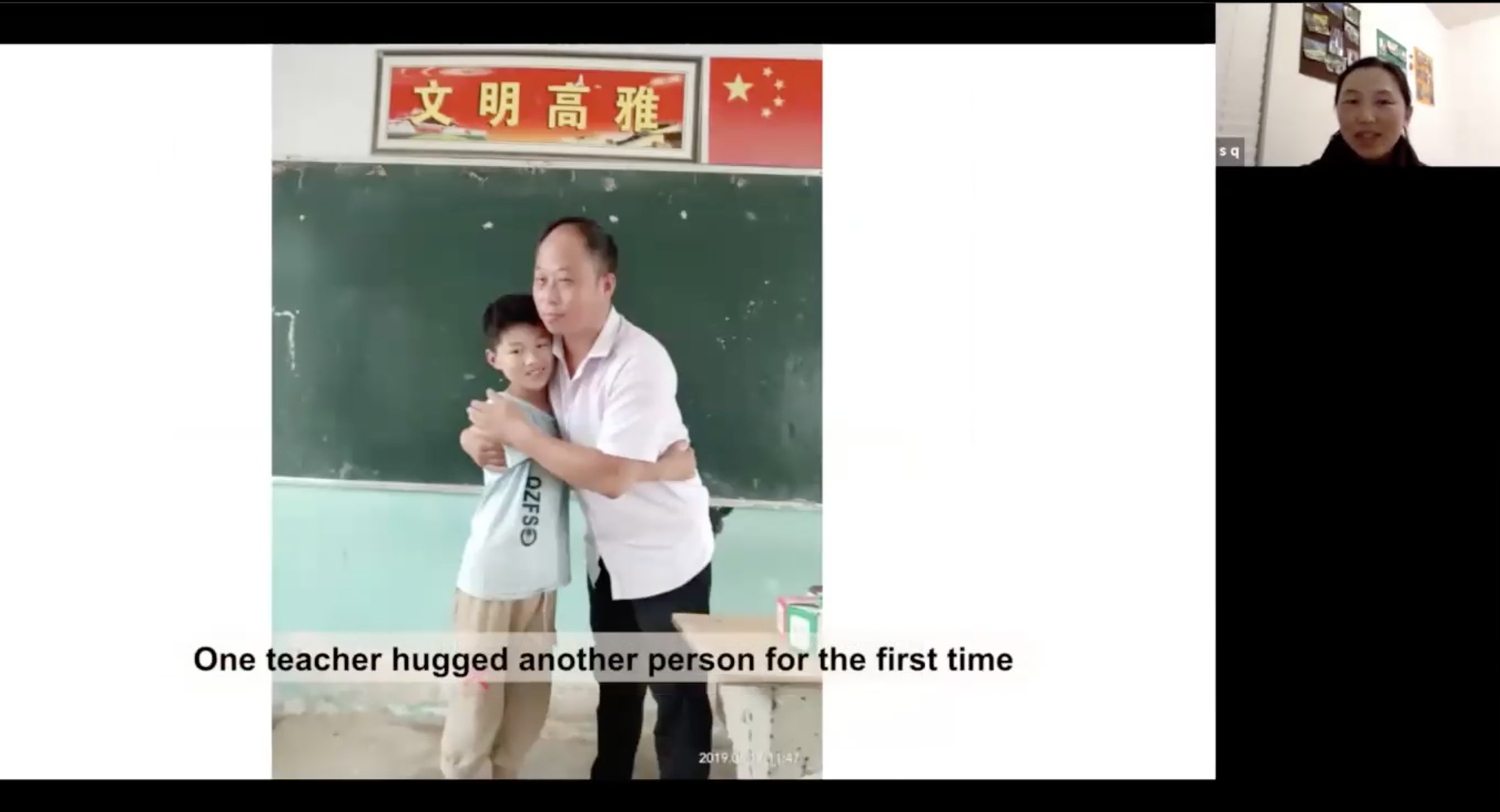 Teacher hugs young student in front of classroom blackboard