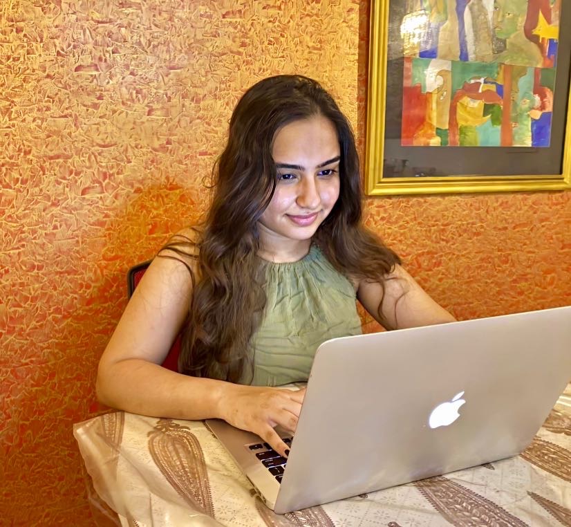 Damya Bhatia sits at a desk working on her computer for her remote internship