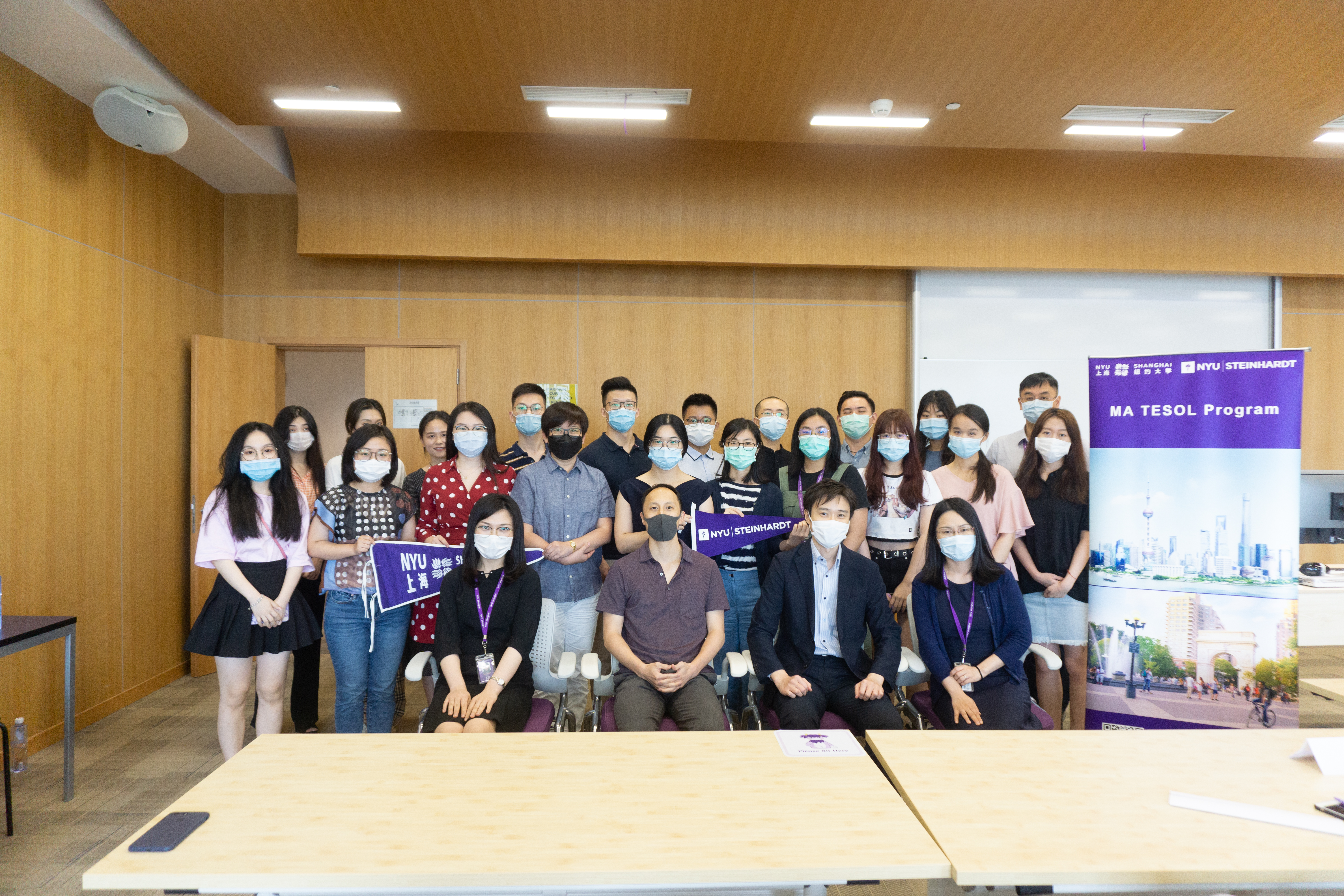 Students and professors pose for group photo wearing masks