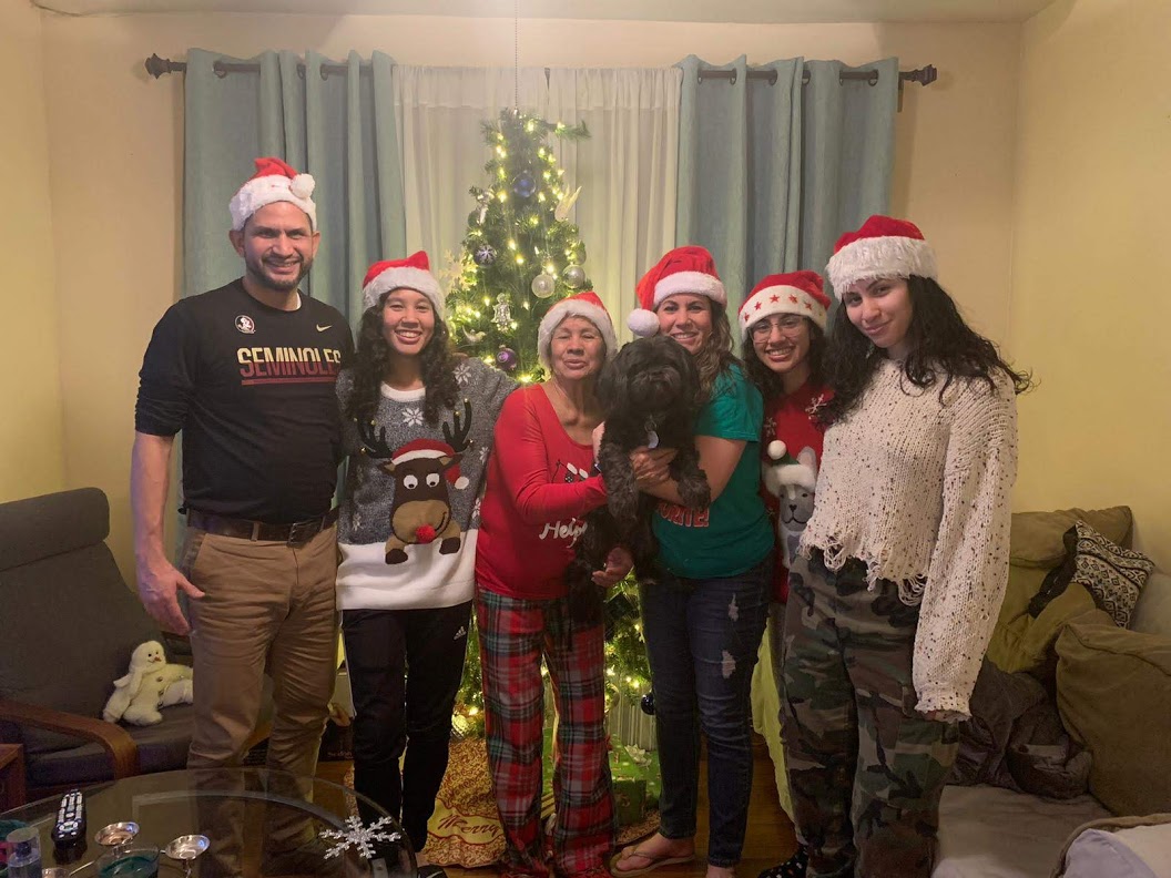 Fontalvo and family wearing Santa hats in front of decorated Christmas tree