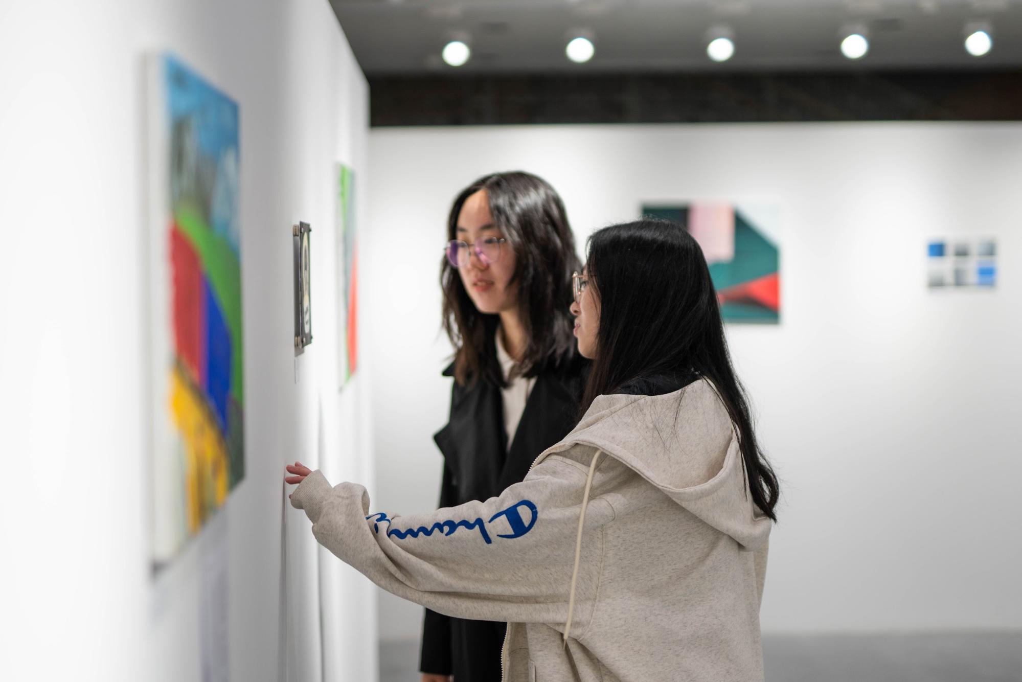 Two students stare closely at a painting in a gallery