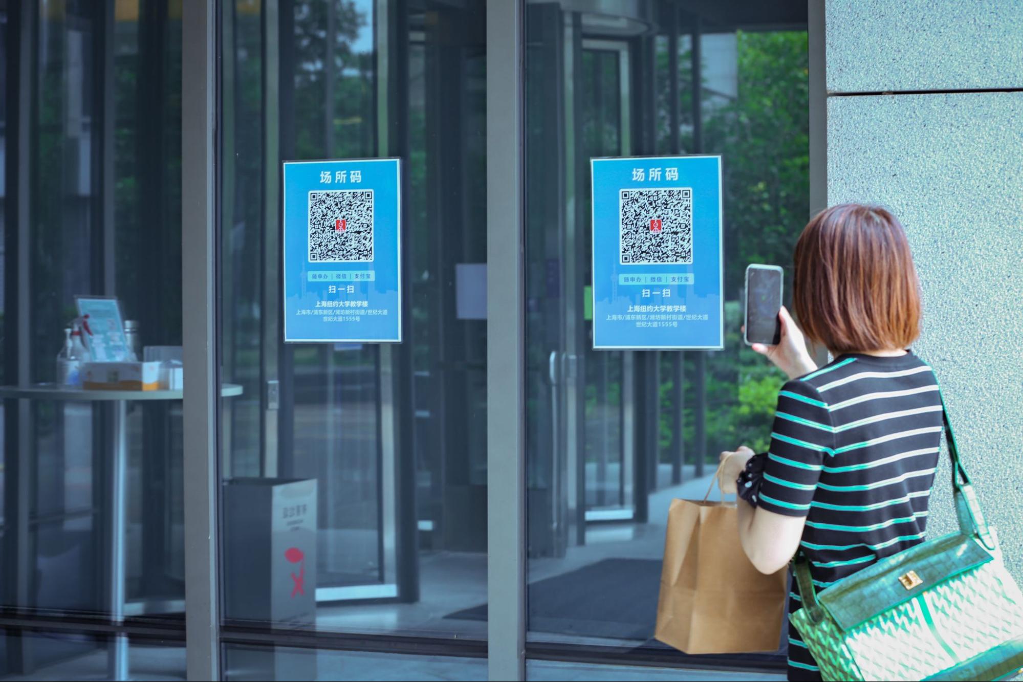 A woman scans the health QR code to enter the building 