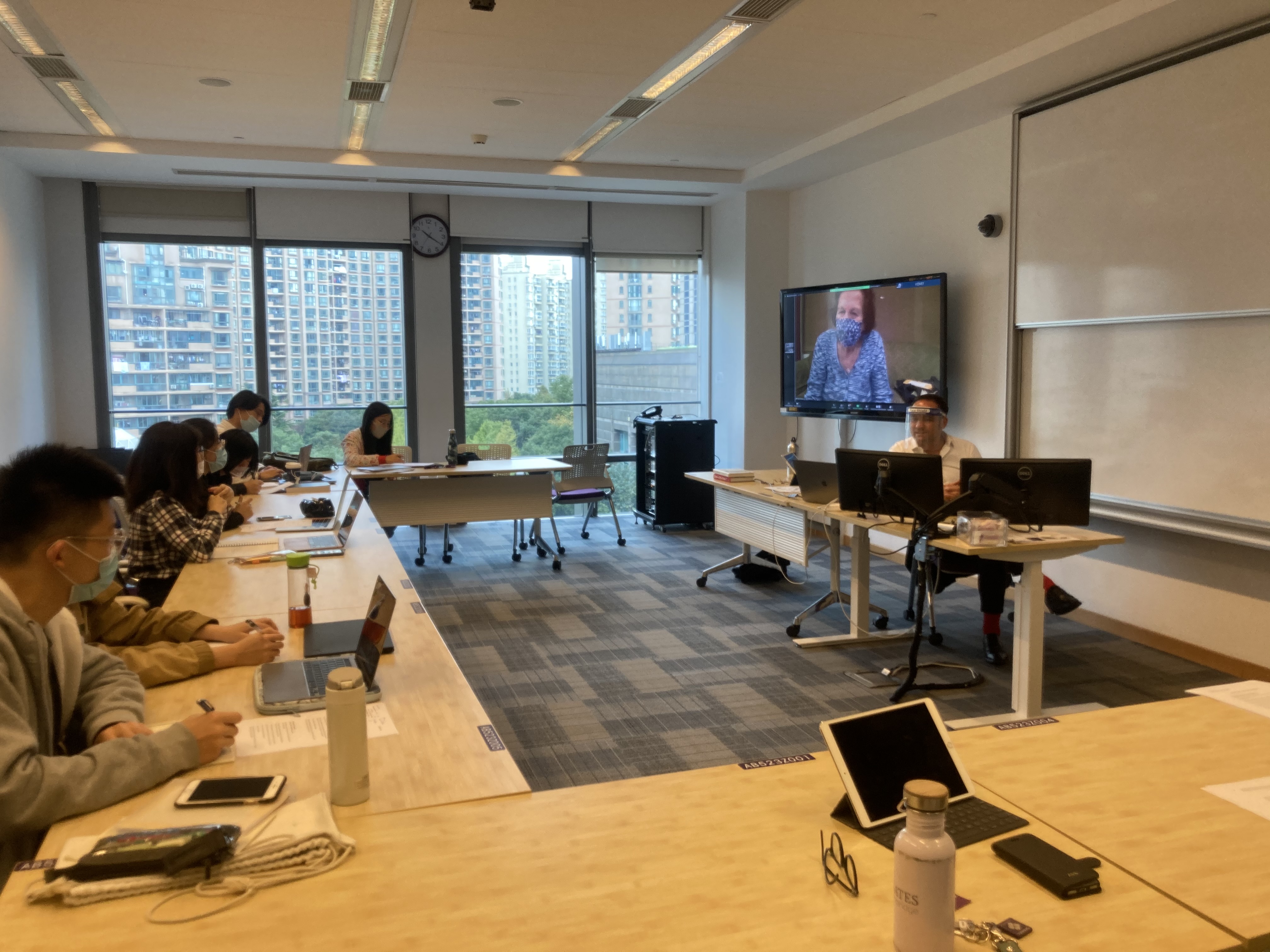 Students in classroom listen to Ruth on large TV screen