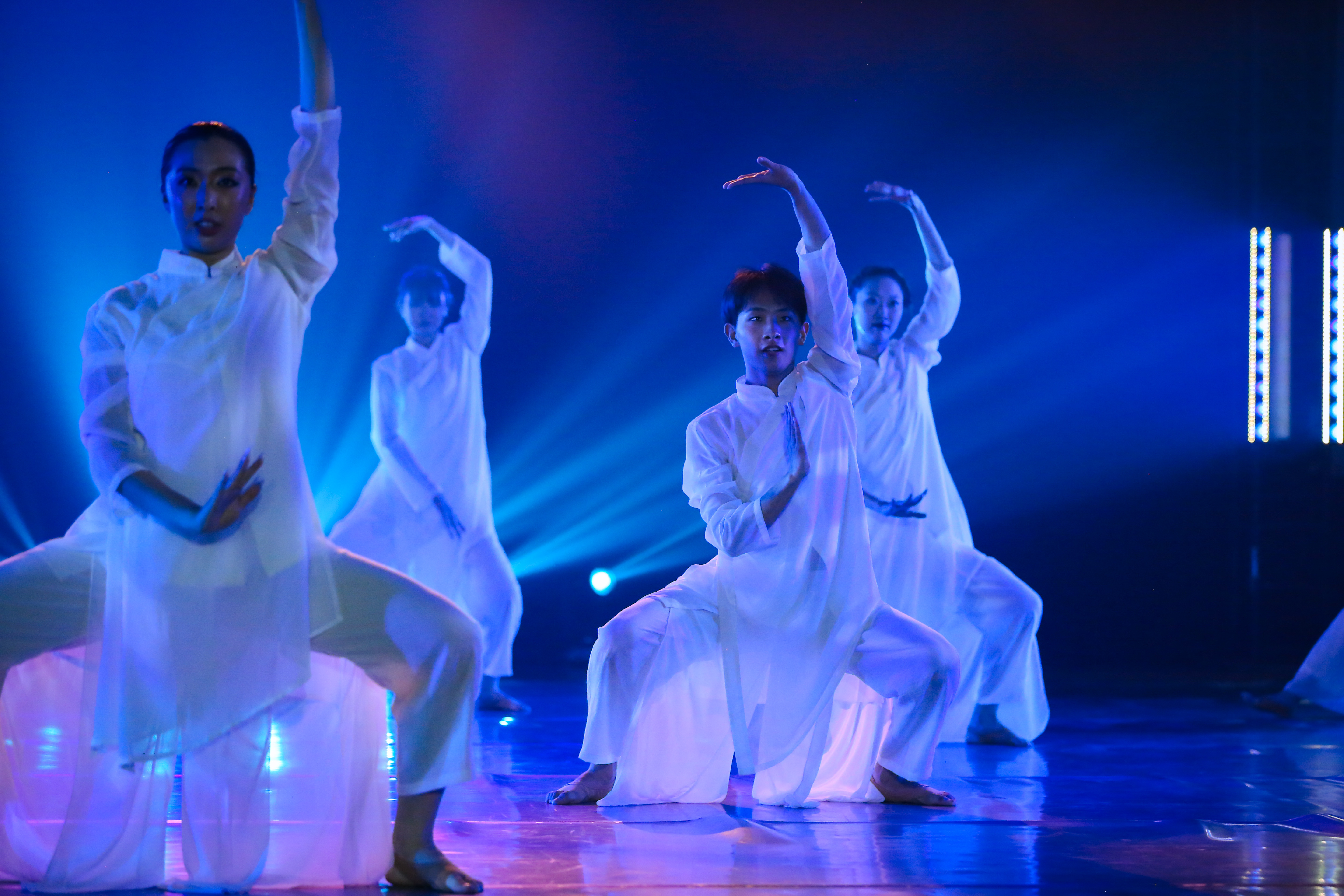 Dancers in flowing white costumes pose 