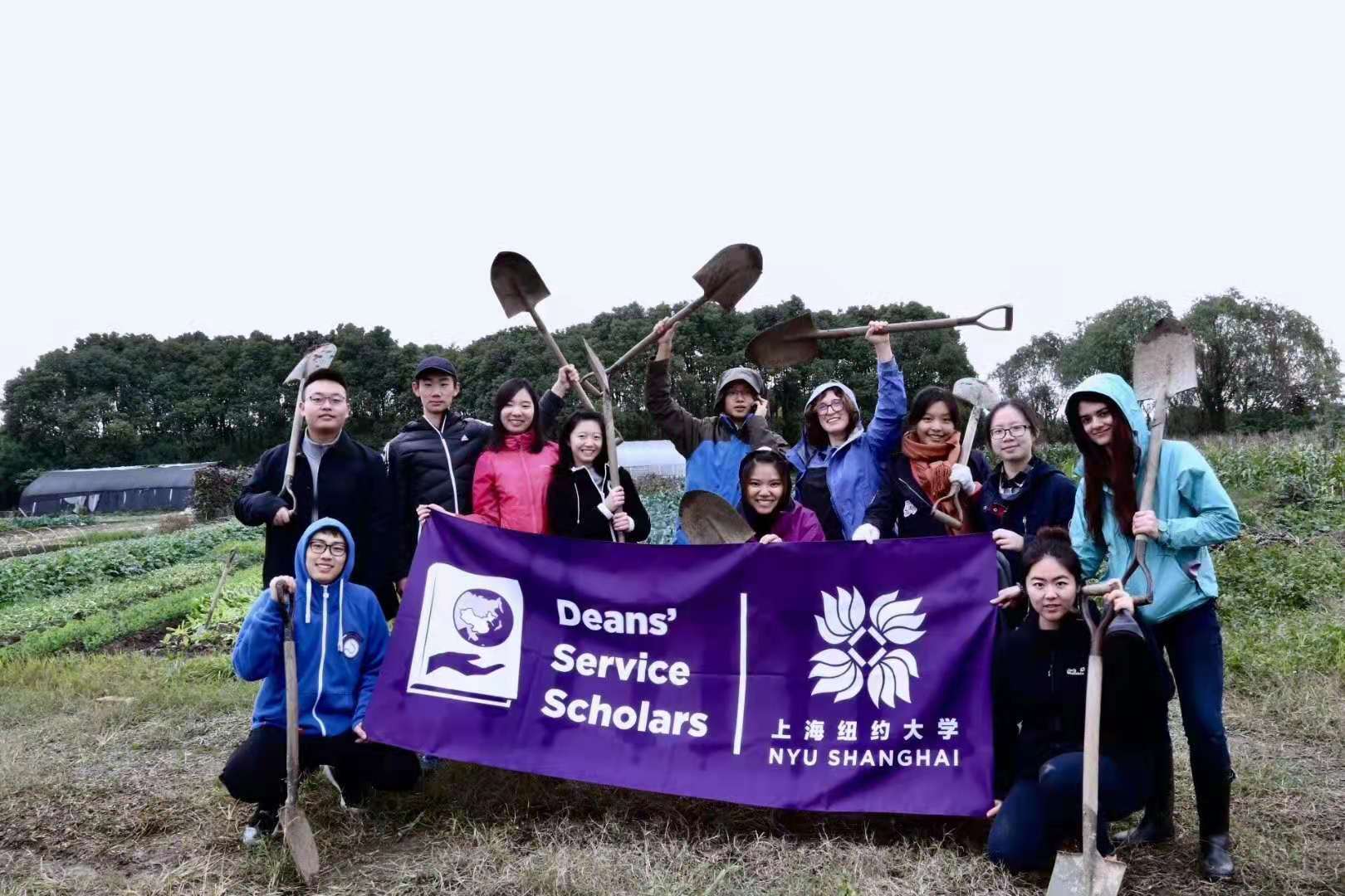 Ma and fellow volunteers wave shovels and pose in field with NYU Shanghai purple banner