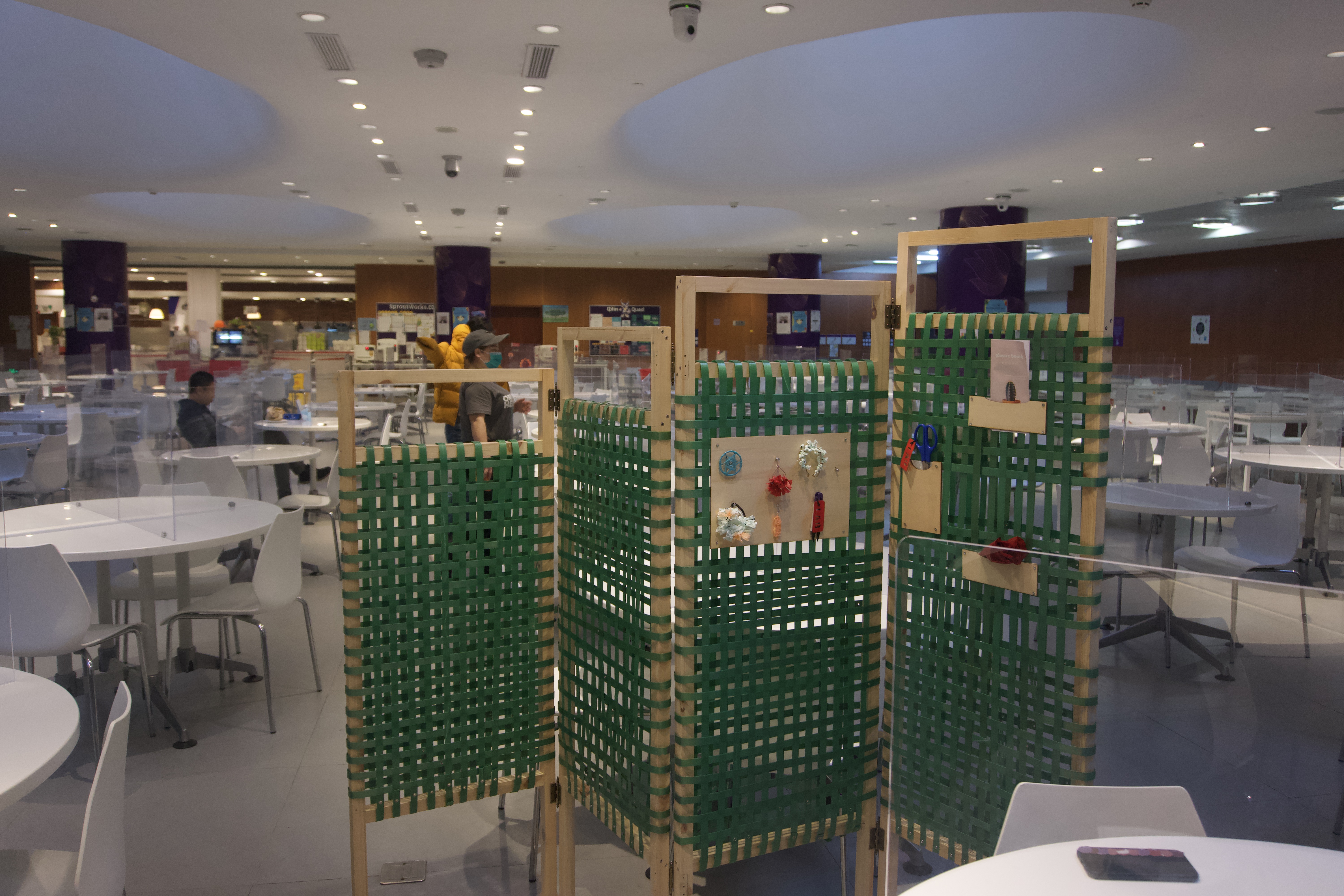 A green folding screen in the middle of NYU Shanghai's B1 cafeteria. Kong designed this with her classmates to give workers a private rest space