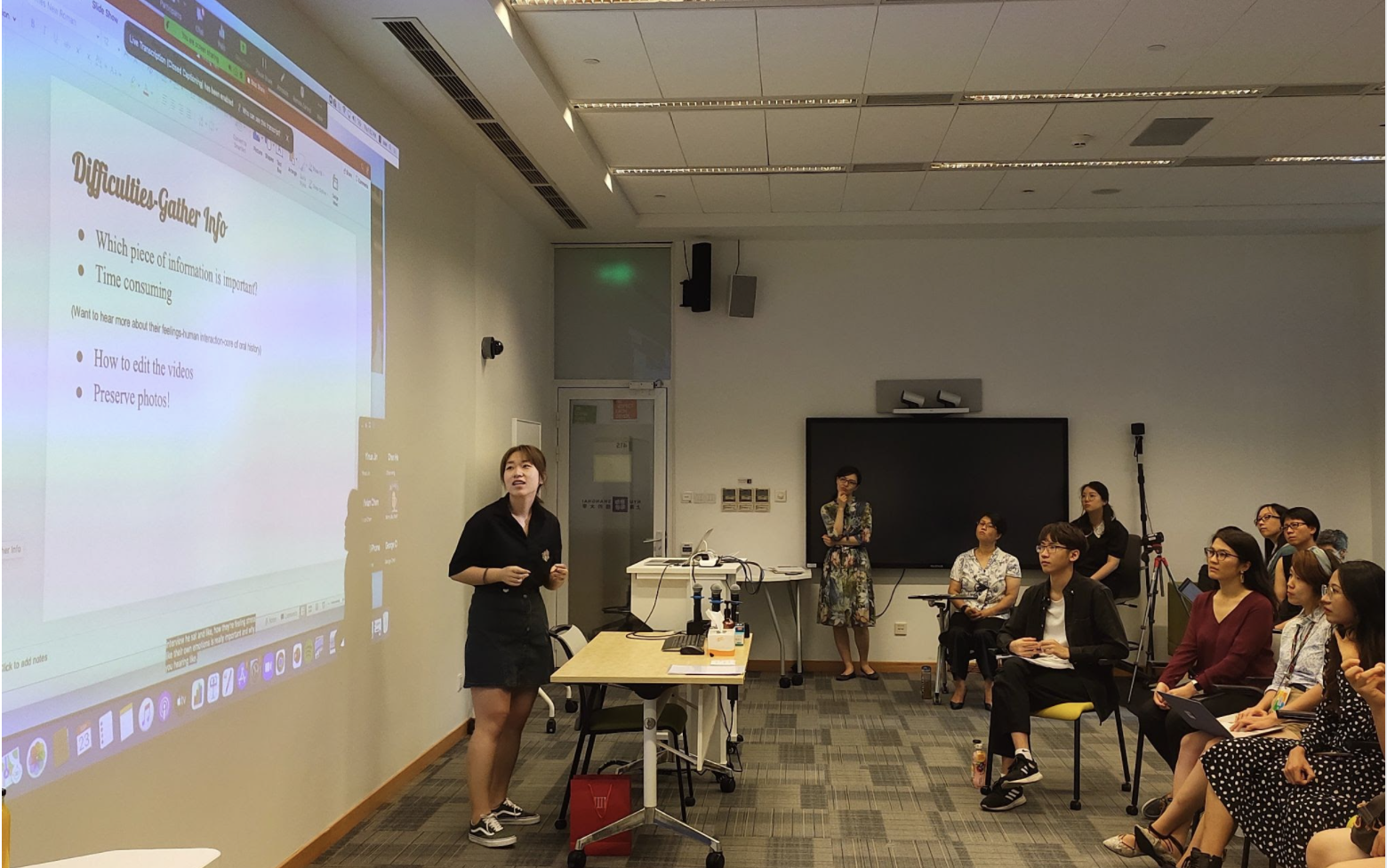 Student gestures toward presentation screen as audience listens attentively