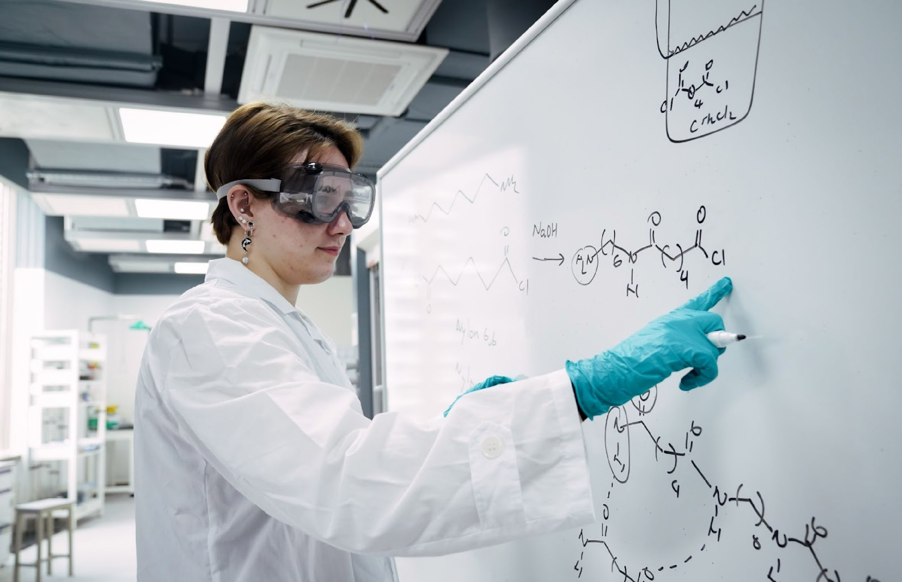 Carter in the chemistry lab standing at a whiteboard and writing equations 