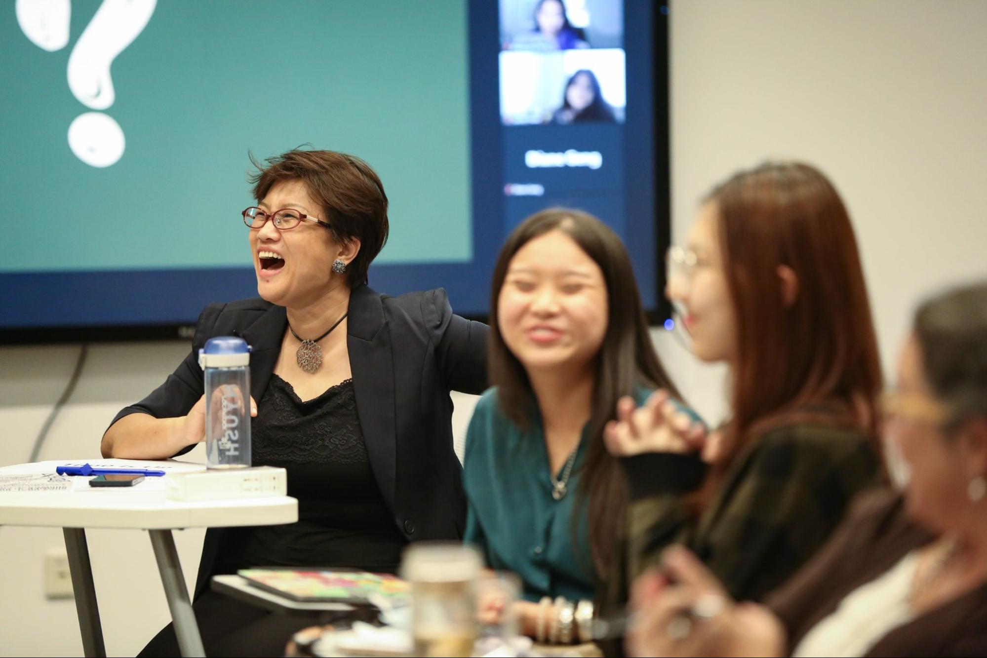 Professor Wen and students smile and laugh in the audience. 