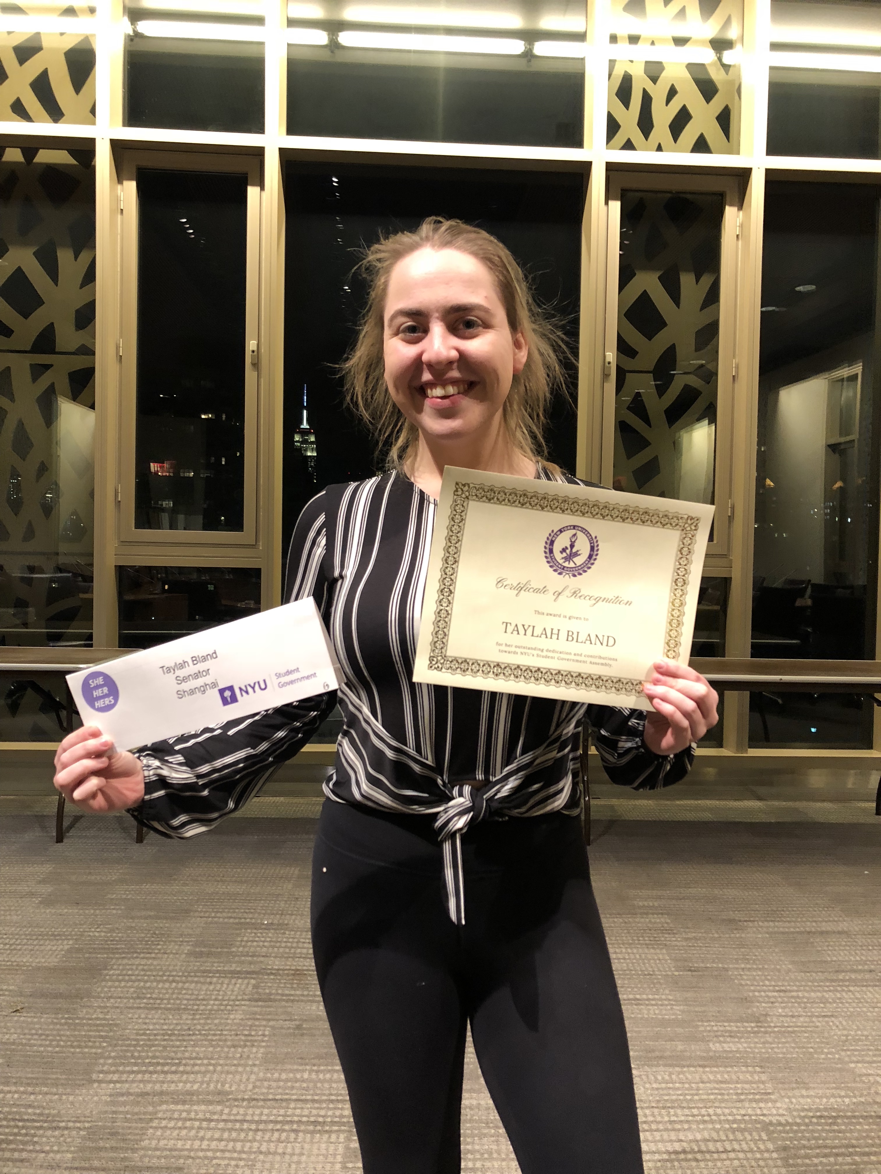 Bland holds recognition award and NYU Senator nameplate