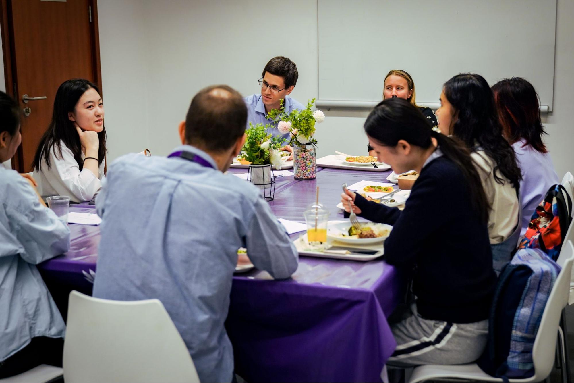 Students and professors seated at a table for lunch and conversation