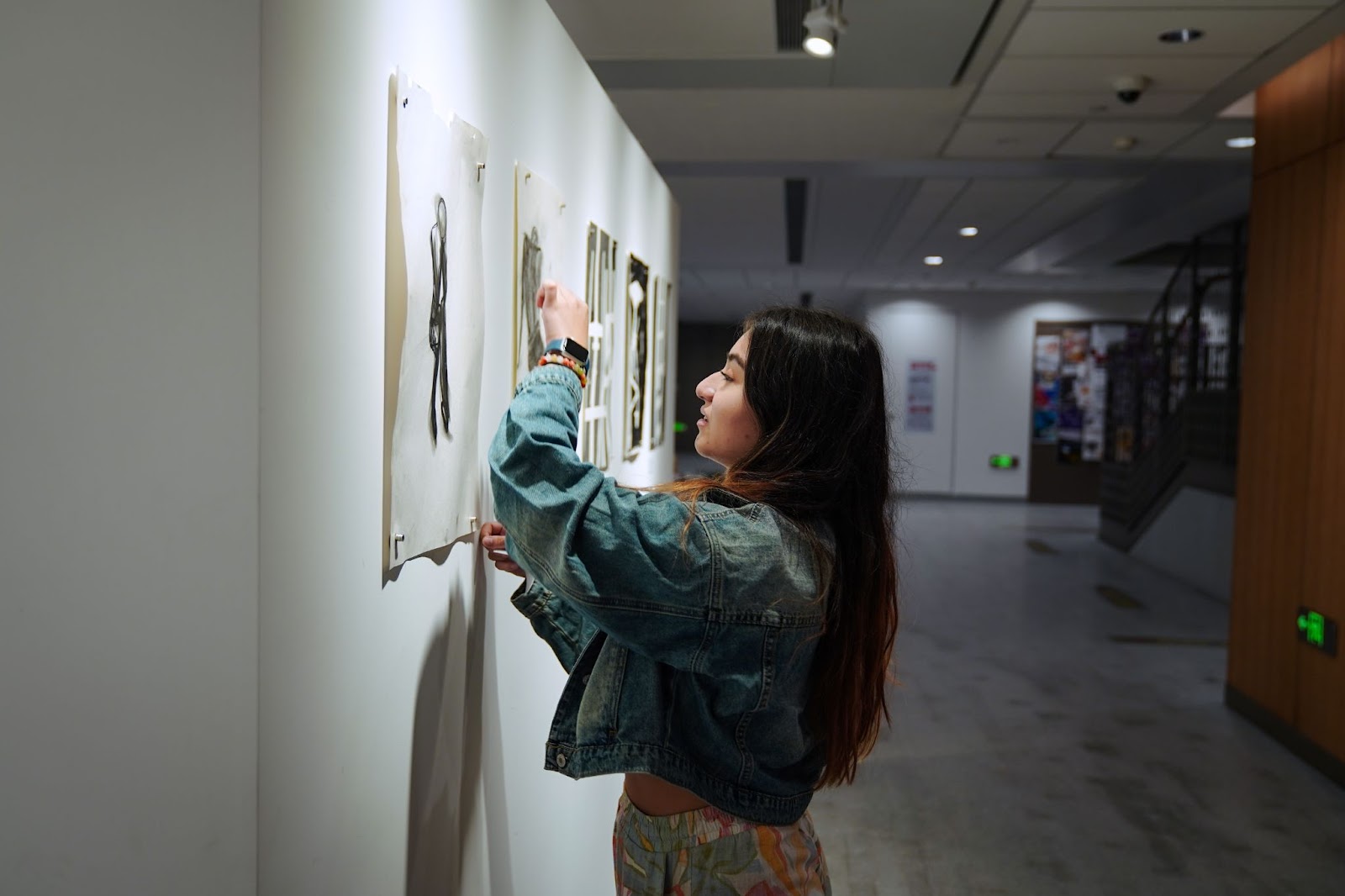 Person with long hair hangs visual art piece on wall 