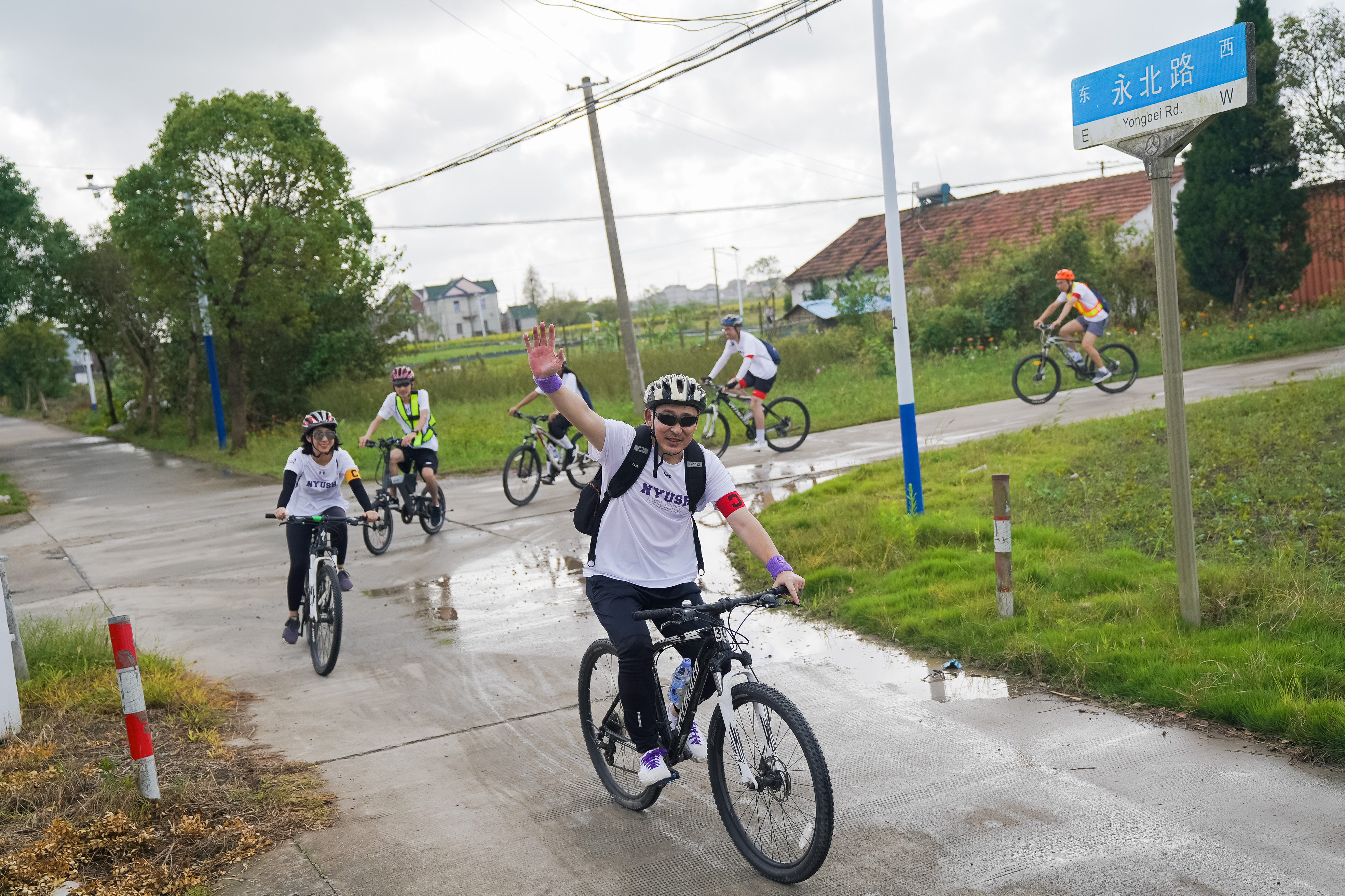 cyclist waves as he rounds corner with group