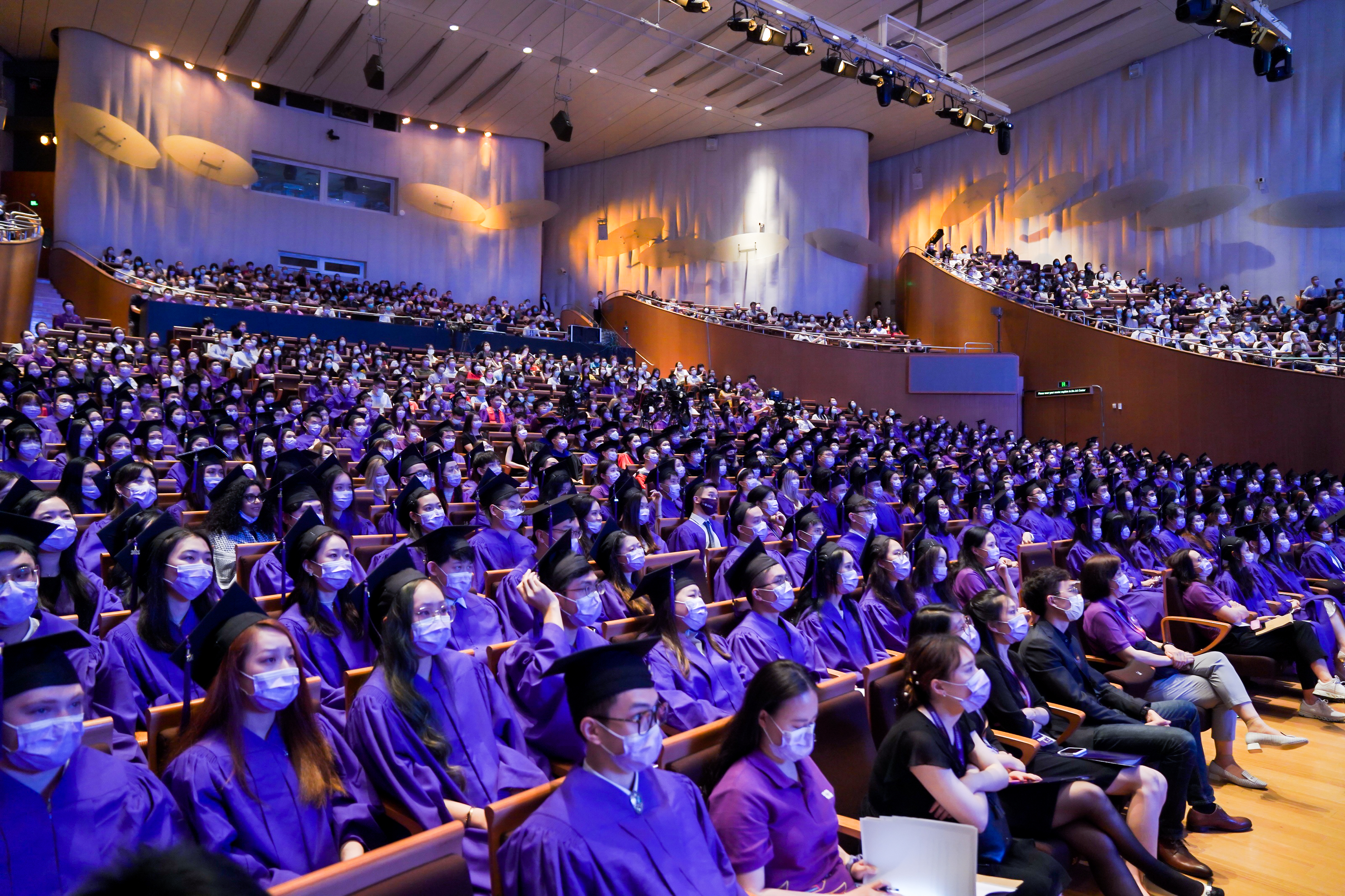 Graduates in purple robes fill theater seats