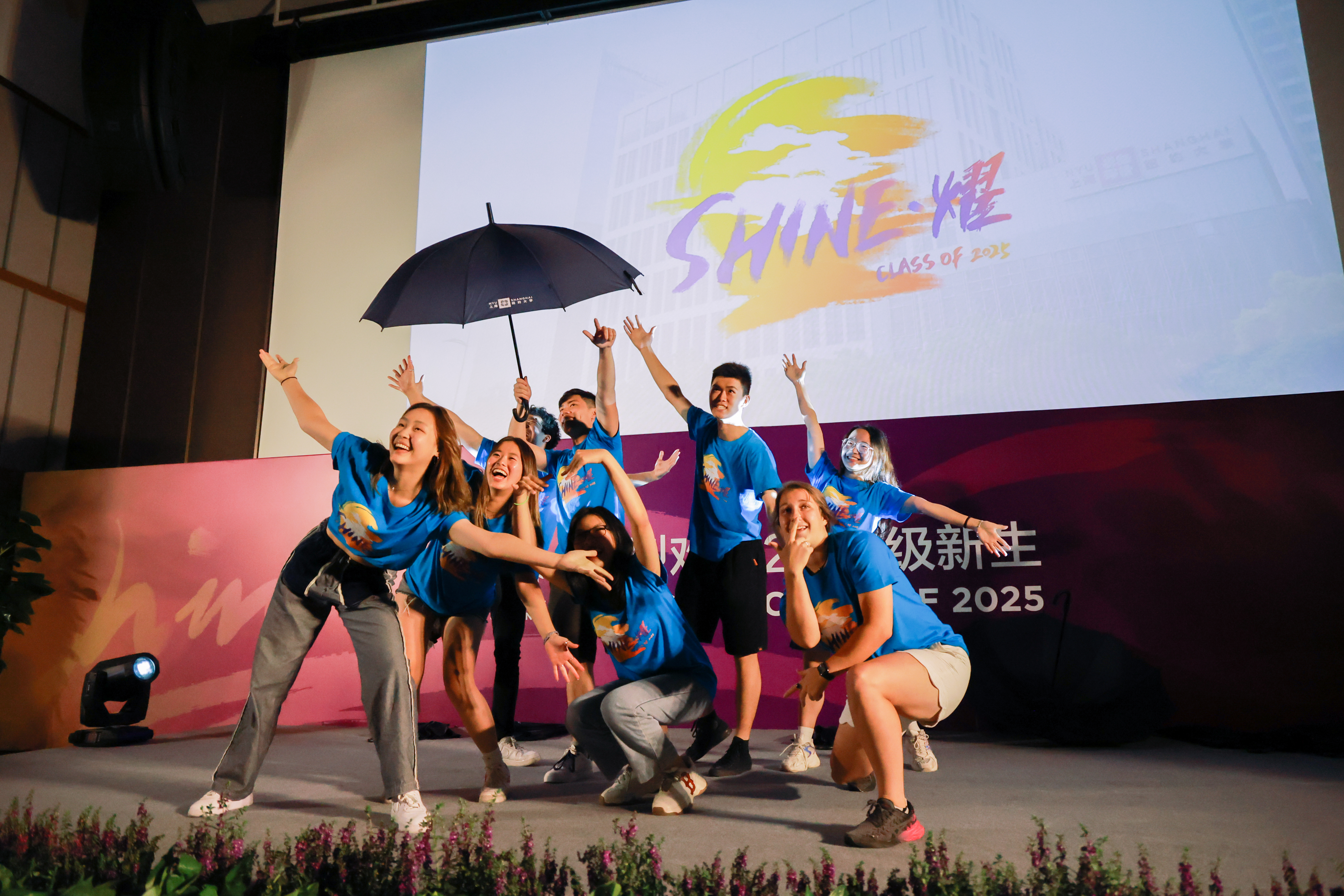 Group of students dance enthusiastically with umbrella prop