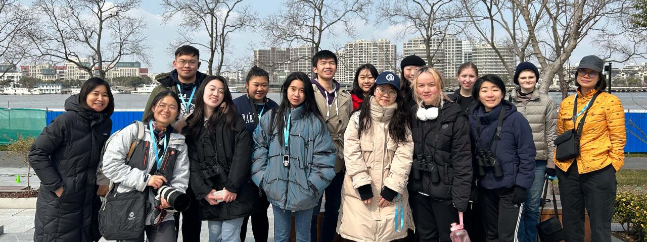 NYU Shanghai staff and students pose with their tour guide at a park in Qiantan