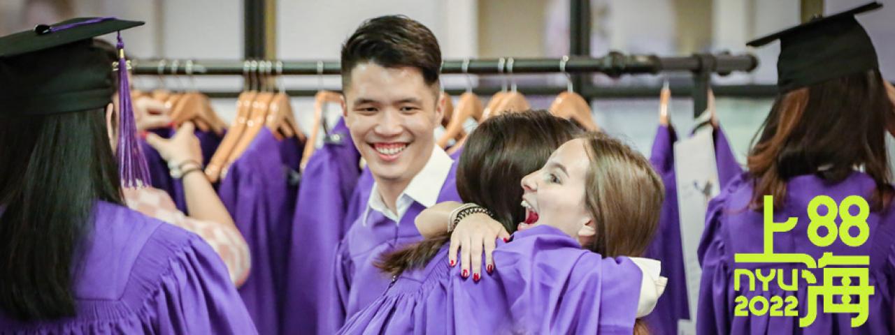 students hug while trying on robes