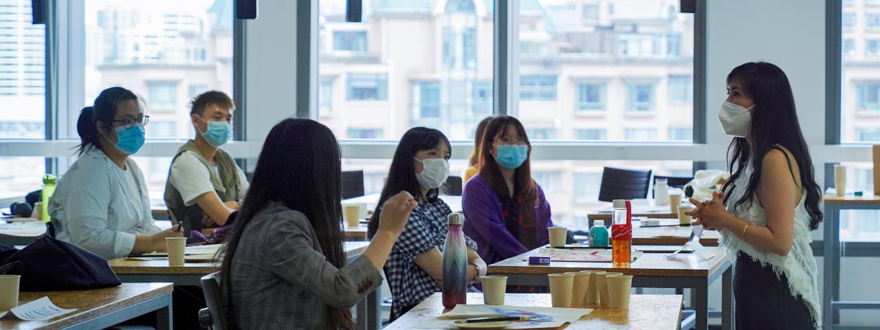 Professor and students engage in classroom discussion while wearing masks