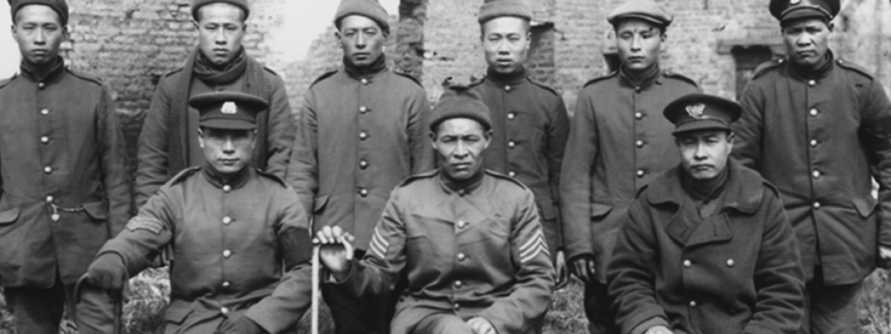 Foremen and workers in military uniform pose in front of shelled-out building