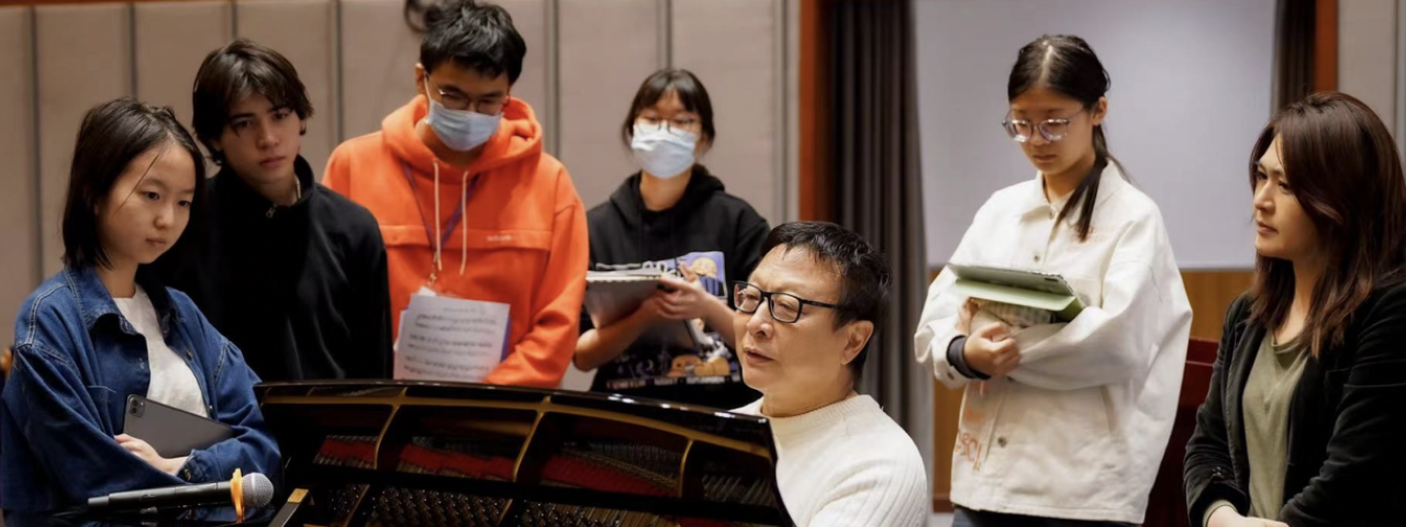 Students gather around Sheng at the Piano