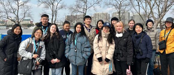 NYU Shanghai staff and students pose with their tour guide at a park in Qiantan