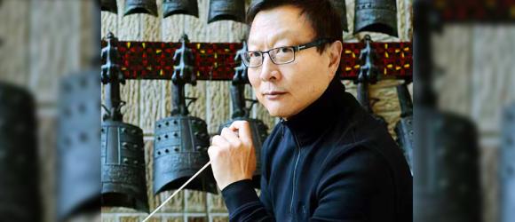 Bright Sheng sitting with his baton