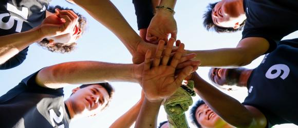 nyu shanghai men's soccer team put their hands together in a huddle