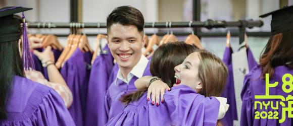 students hug while trying on robes