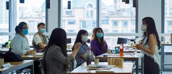 Professor and students engage in classroom discussion while wearing masks