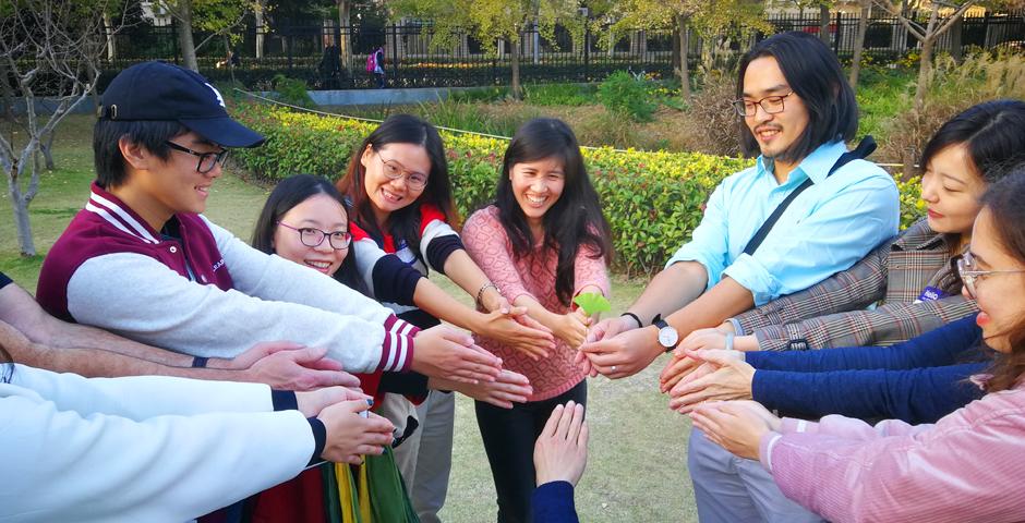 NYU Shanghai students, faculty, and staff join hands to form the shape of a gingko leaf. From left: Murray Lu, Yuan Yanyue, Bi Jinghong, Associate Arts Professor at PCI Emily Tsiang (IMA), Global Awards Coordinator Duke Xu, PCI administrator Michelle Ji, and Citlaly Weed