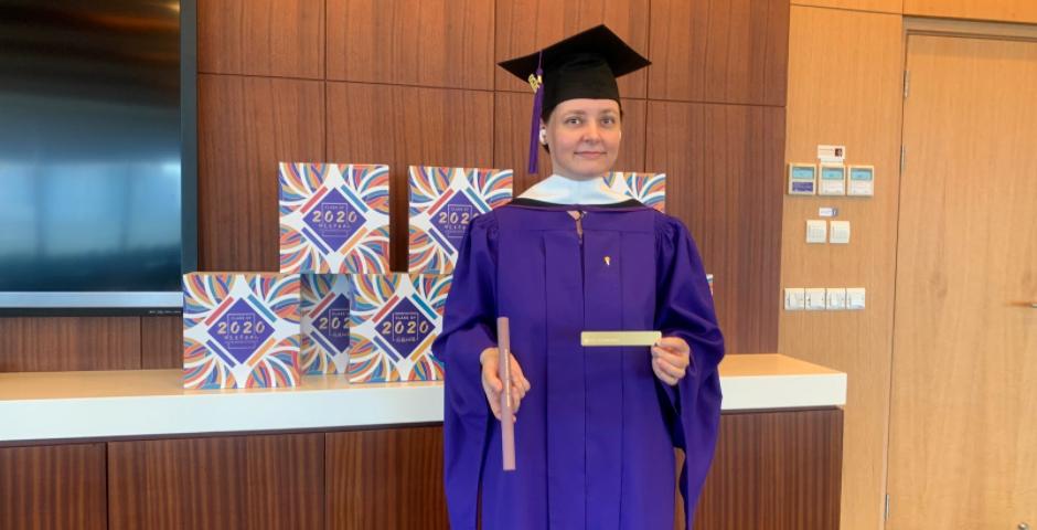 After picking up her gift box, TESOL graduate Natalya Likhacheva, MA ‘20, dons her gown, hood, cap, and tassel.