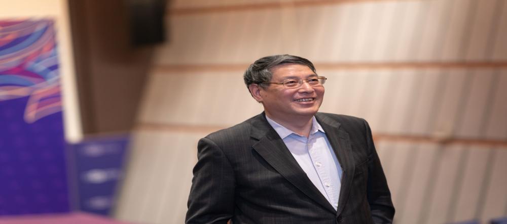Smiling Chancellor Yu walks up NYU Shanghai auditorium steps.