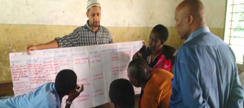 Yunus talking with people and holding a large piece of paper