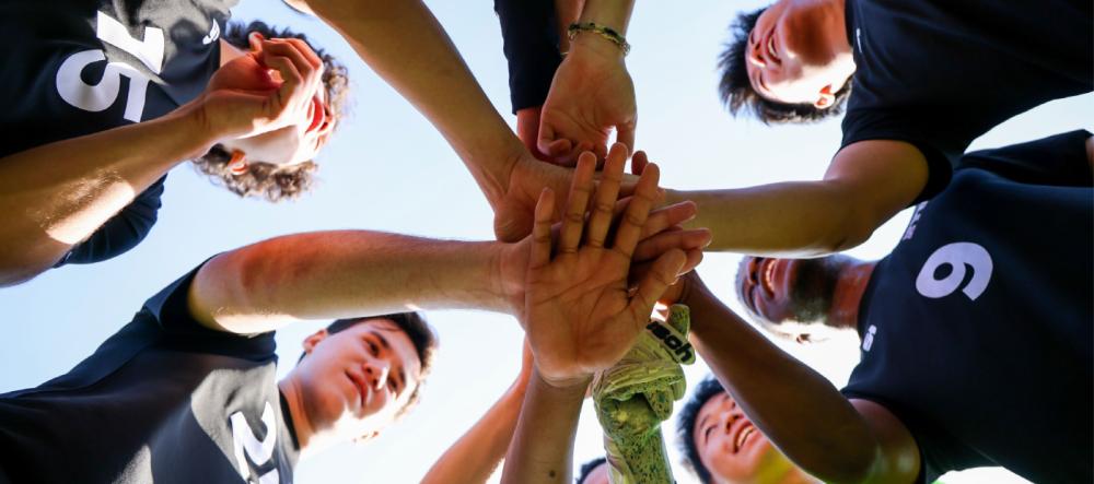 nyu shanghai men's soccer team put their hands together in a huddle