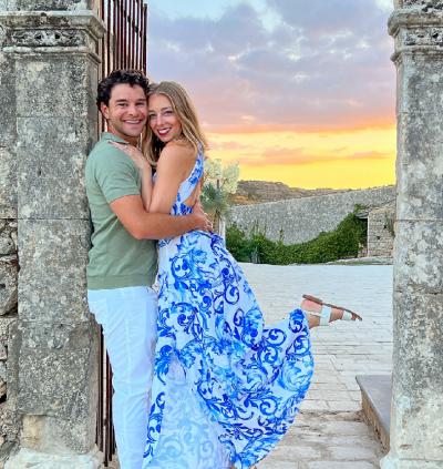 Julie and Max embrace before a sunset on their honeymoon in Italy