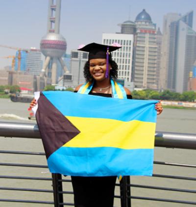 Glinton holds Bahamian flag as she poses with Lujiazui skyline in the background