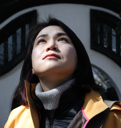 Zuo looks pensively up under shadow of buildings