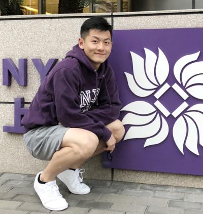 Cai in front of the NYU Shanghai sign on Century Ave during his first semester.