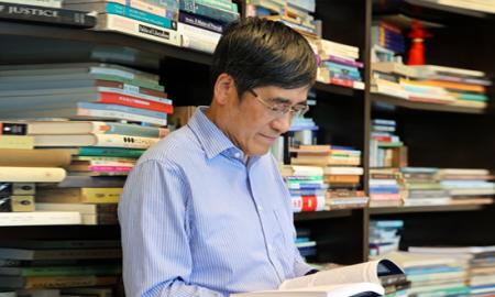 Tong reads in front of full bookshelves