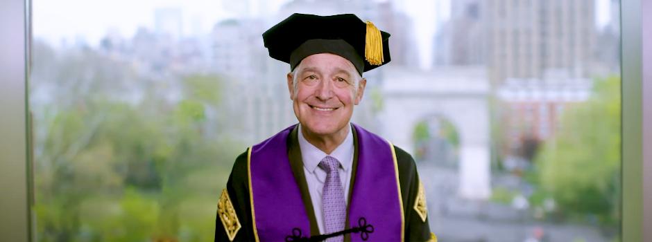 NYU president Andrew Hamilton wearing NYU regalia and giving a speech 