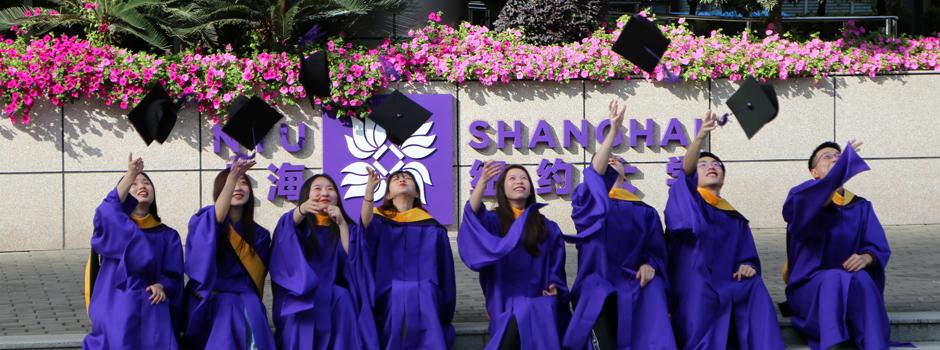 Students toss caps in front of NYUSH sign